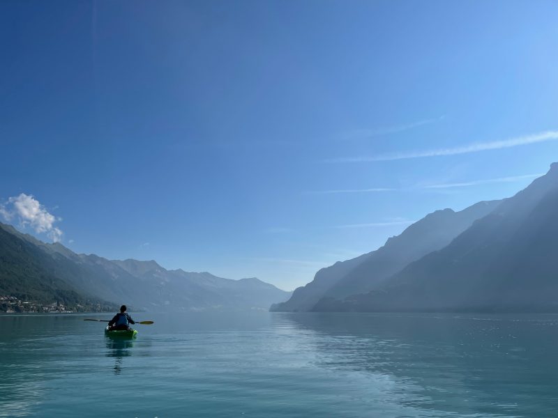 a person kayaking on a calm lake surrounded by mountains